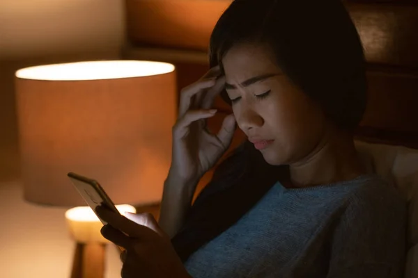 Stress-Asiatin liegt mit Smartphone im Bett — Stockfoto