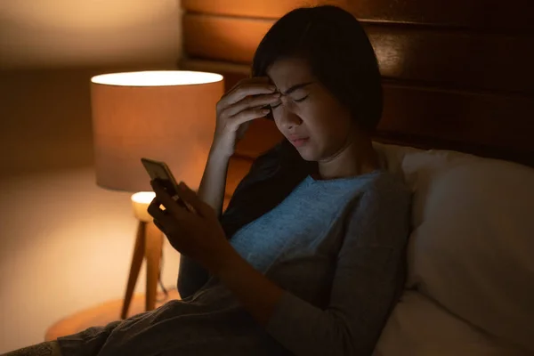 Stress asiatisk kvinna ligger i sängen med smartphone — Stockfoto