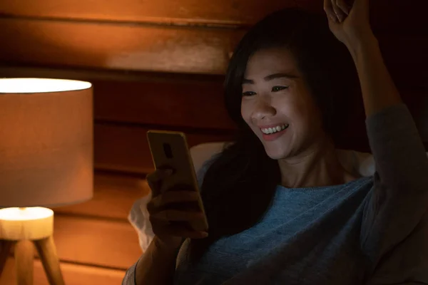 Kvinnan ler medan du använder sin smartphone — Stockfoto