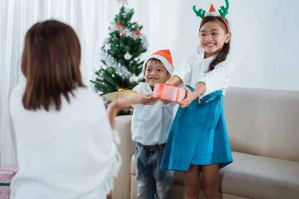 Filha e filho dando um presente para a mãe no dia de Natal — Fotografia de Stock