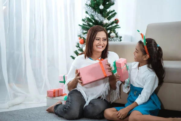 Mãe e filha sorriem ao segurar um presente — Fotografia de Stock