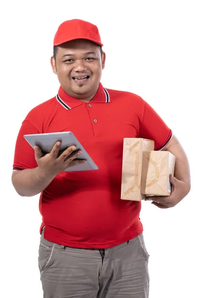 Retrato de hombre joven con uniforme rojo entregando cajas y sosteniendo tableta digital — Foto de Stock