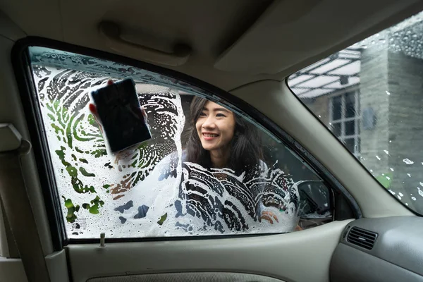 Γυναίκα πλένετε το παράθυρο του αυτοκινήτου με σαπούνι — Φωτογραφία Αρχείου