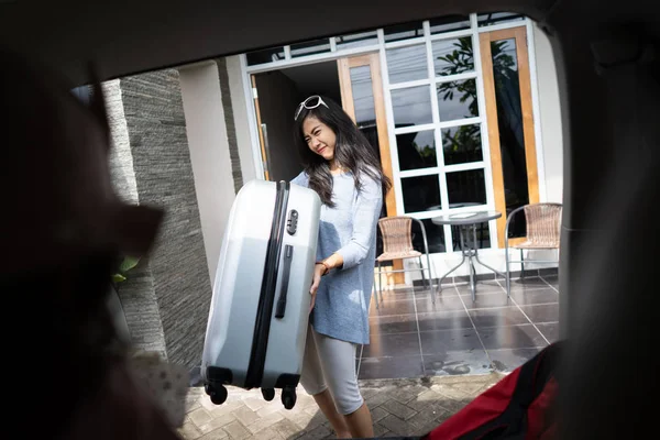 Vrouw wil een koffer in de auto kofferbak — Stockfoto