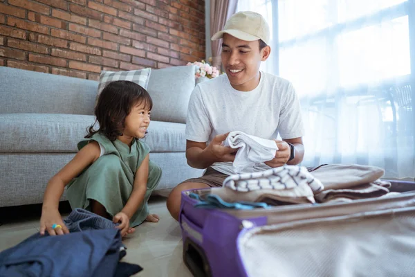 Filha ajudando seu pai a colocar roupas para a mala — Fotografia de Stock