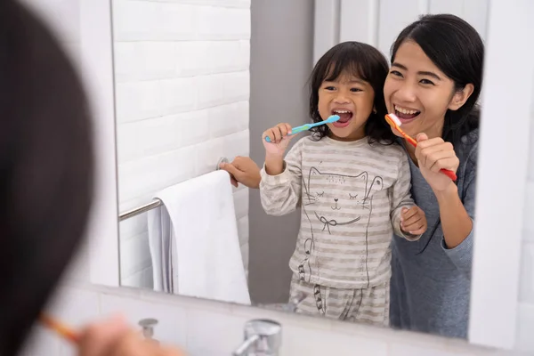 Mãe e criança escovando os dentes juntos — Fotografia de Stock