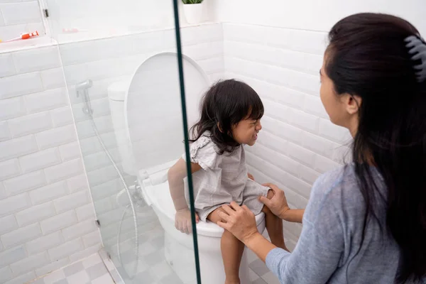 Madre ayudar a su hija a sentarse en el inodoro — Foto de Stock