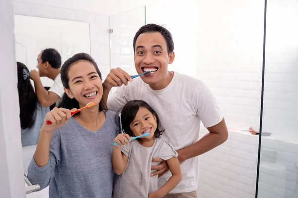 Счастливая азиатская семья чистить зубы вместе — стоковое фото