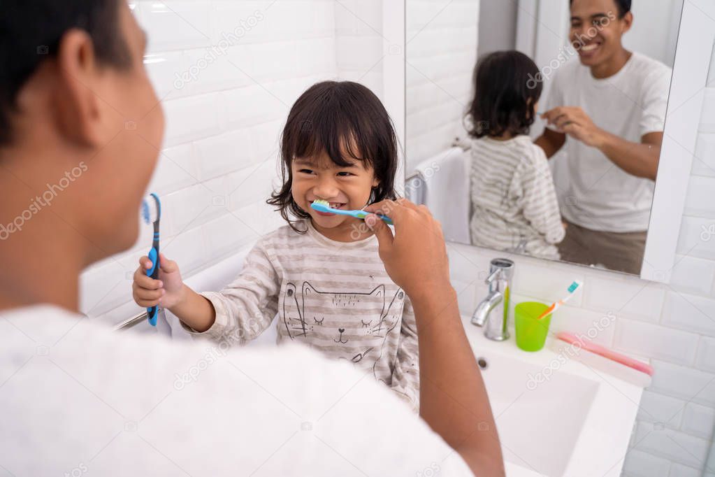 kid and dad having fun while brushing their teeth
