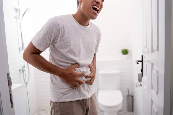 Man houdt zijn maag pijnlijk in het toilet — Stockfoto