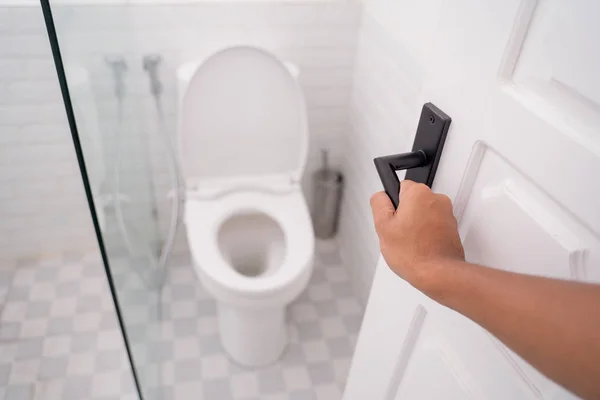 Hand opening the toilet door — Stock Photo, Image