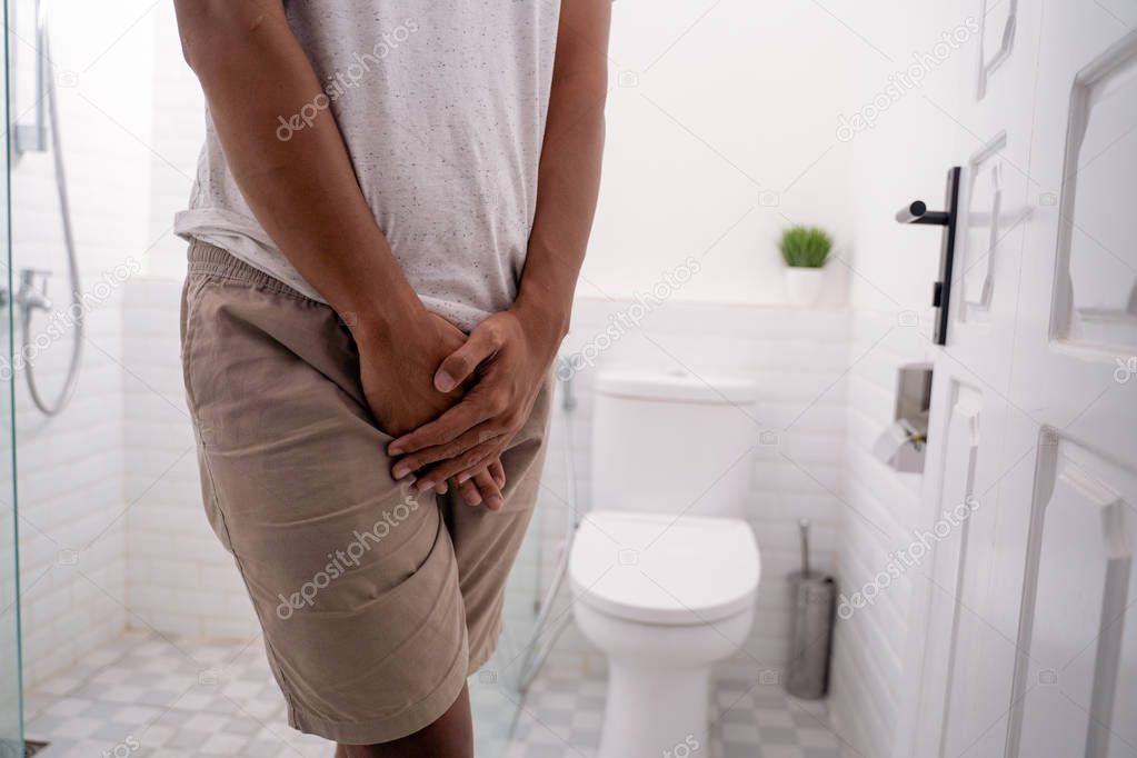 man hold his genitals in the toilet
