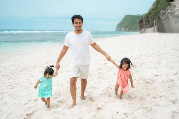 Padre cogido de la mano dos hija en la playa —  Fotos de Stock