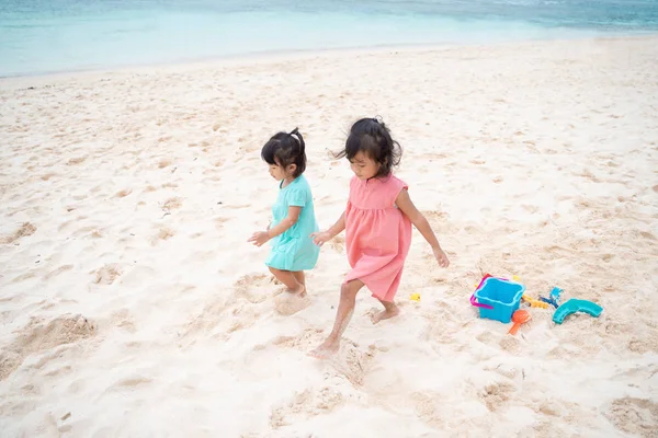 Zwei kleine Mädchen gehen zusammen am weißen Sandstrand — Stockfoto
