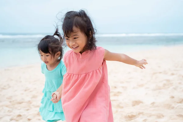 흰 모래 해변에 산책 하는 때 두 어린 소녀는 손을 잡으십시오 — 스톡 사진