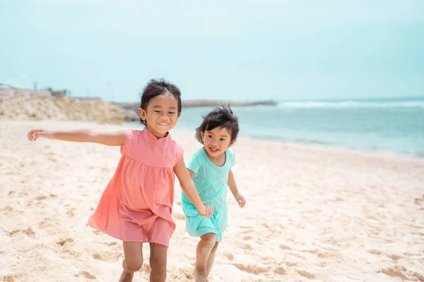 Zwei kleine Mädchen gehen zusammen am weißen Sandstrand — Stockfoto