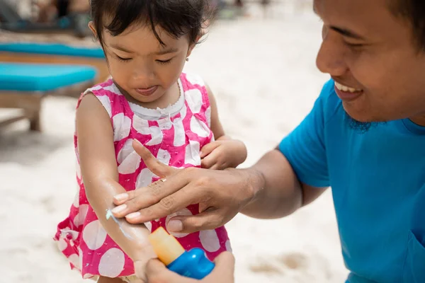 Retrato padre frotando un protector solar a hijas brazo — Foto de Stock