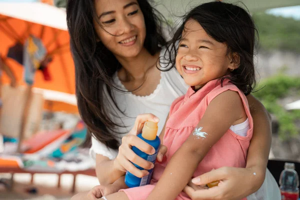 A daughter feels amused when mother give a sunblock to his arm — Stock Photo, Image