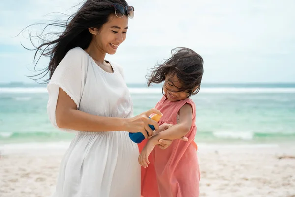 Uma filha feliz porque sua mãe dar protetor solar para o seu braço de pele — Fotografia de Stock