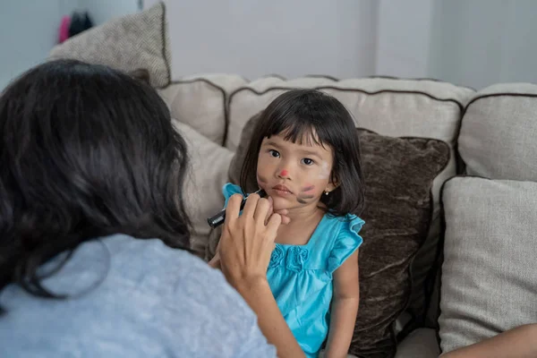 asian mother face painting her little daughter