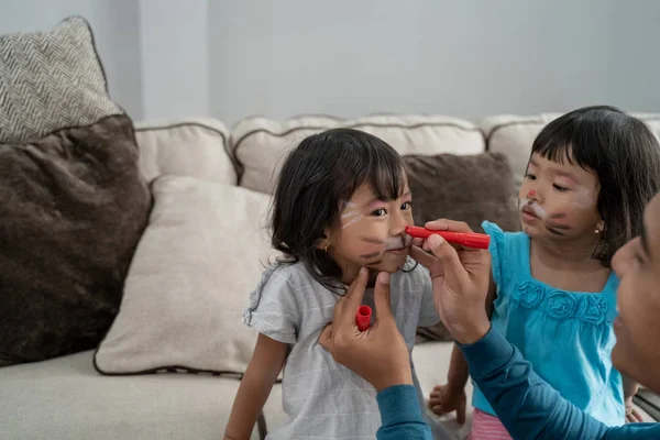 Papá haciendo un poco de pintura facial en rostros de hijas — Foto de Stock