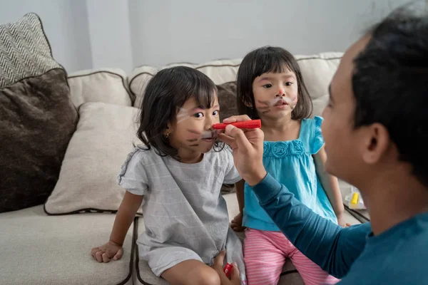 아버지는 얼굴에 그의 두 딸을 페인트 — 스톡 사진