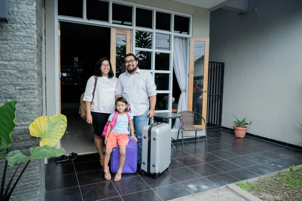 Famiglia con valigia in piedi davanti alla loro casa — Foto Stock