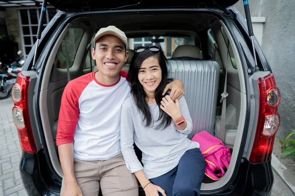 Pasangan duduk di atas bagasi mobil tersenyum bersama — Stok Foto