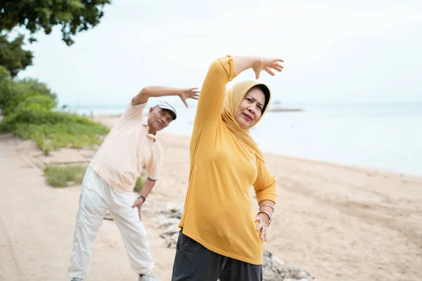 幸せな上級アジア男と女一緒にビーチで自分の体をストレッチ — ストック写真
