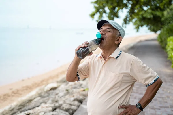 Senior mannelijke Aziatische drinkwater fles — Stockfoto