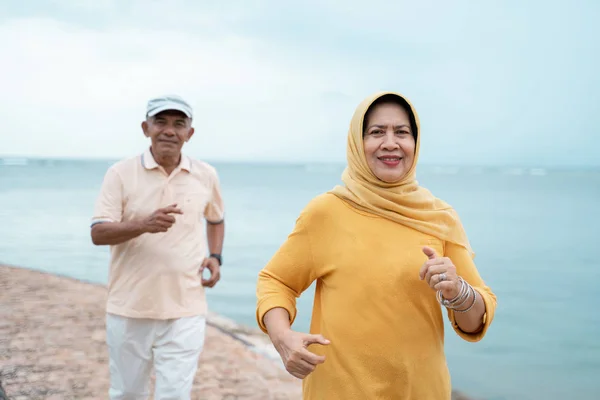 Muslimské staré pár cvičení a běh na pláži — Stock fotografie