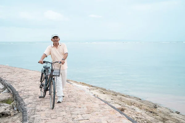 Asiatisch alt mann reiten sein bike bei die strand — Stockfoto