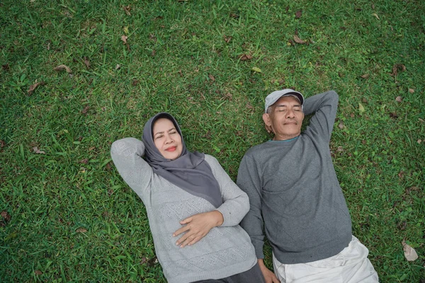 Pasangan senior muslim asia berbaring di atas rumput — Stok Foto