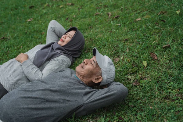 Starší muž a žena ležící na trávě — Stock fotografie
