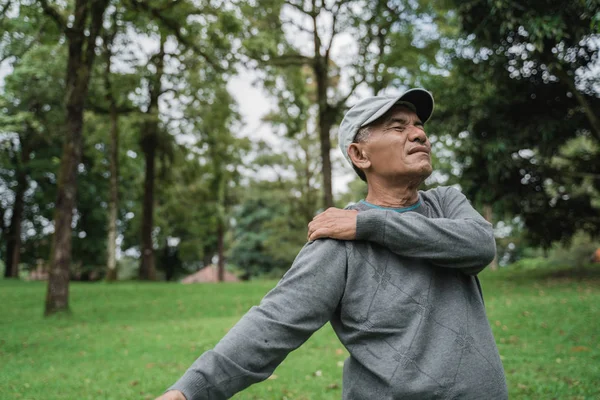 Senior macho asiático teniendo dolor de hombro y dolor en su articulaciones —  Fotos de Stock