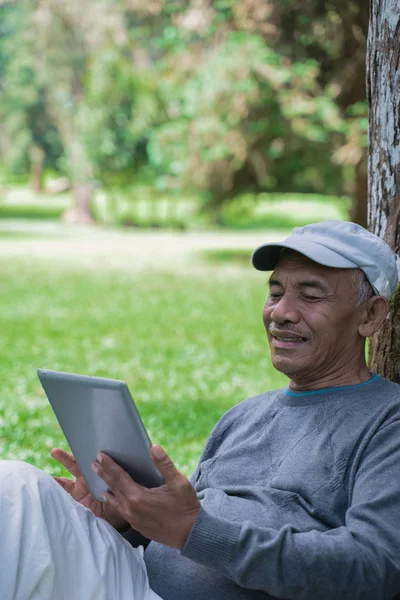 senior old man using tablet pc in the park