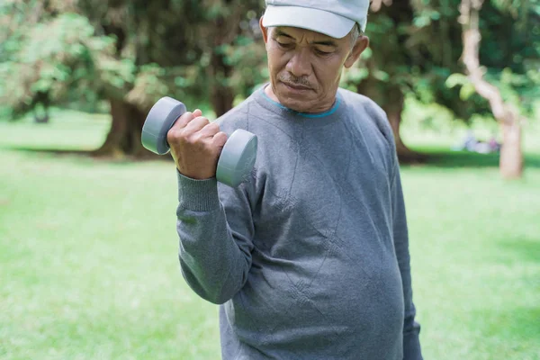 Viejo asiático hombre usando dumbell en el parque —  Fotos de Stock