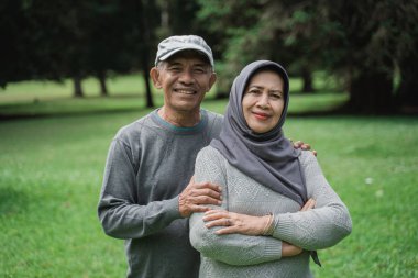 parkta gülümseyen ve kameraya bakarak Müslüman çift