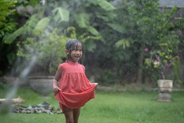 Niño disfrutando jugando con salpicaduras de agua en el jardín —  Fotos de Stock