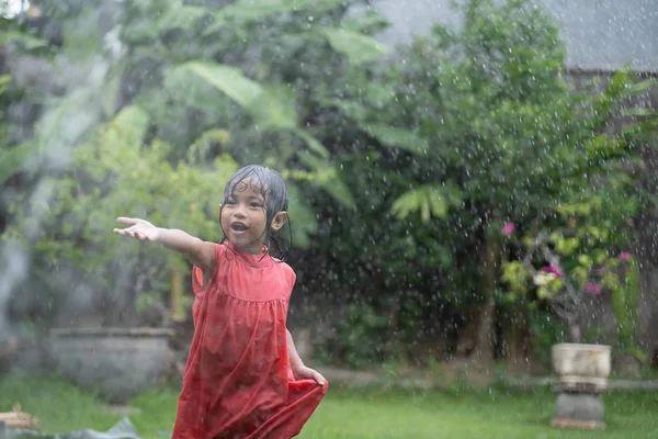 庭の水より雨と演奏を楽しんで子供の肖像画 — ストック写真