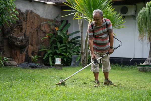 Velho asiático homem cortando seu jardim — Fotografia de Stock