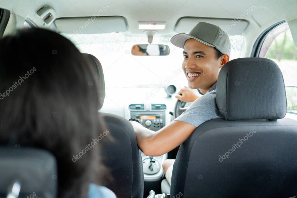 man driver look back to woman passenger to asking of destination