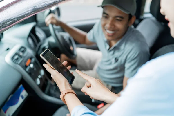 Portrait of passenger showing his smartphone application to the driver — Stock Photo, Image