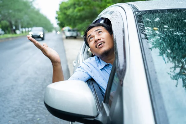 asian young driver opened the window and watched the sky will be rain