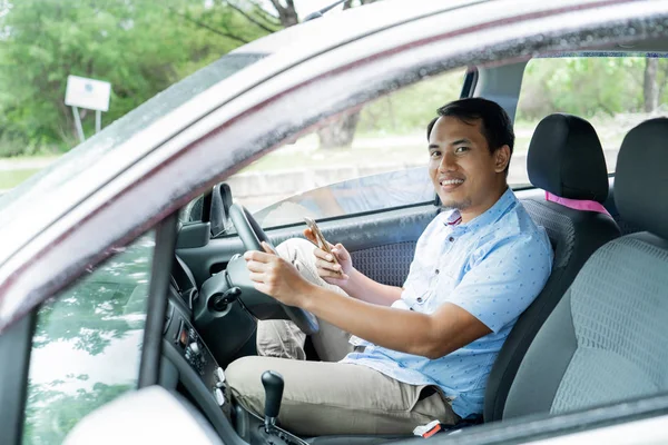 Молодой человек водитель расслабиться внутри автомобиля с помощью смартфона — стоковое фото