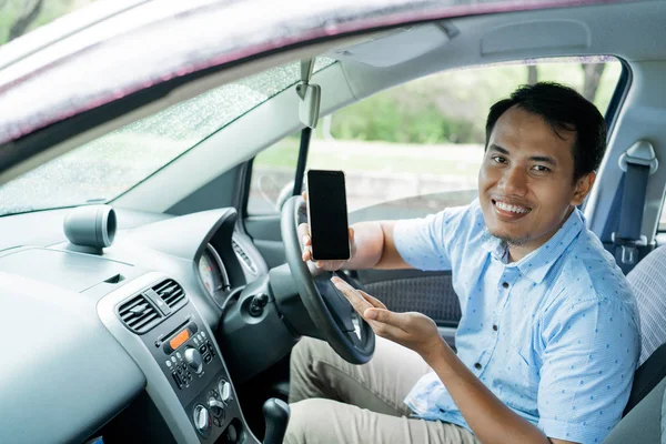 Водитель онлайн такси в машине показывая смартфон — стоковое фото