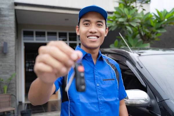 Mechanic holding car key and smiling — стоковое фото