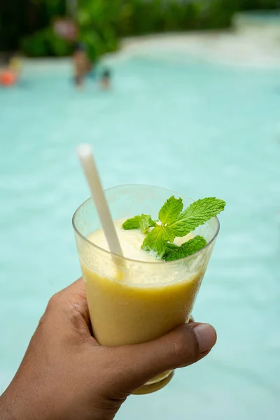 Een hand met een glas verse banaan melk SAP — Stockfoto