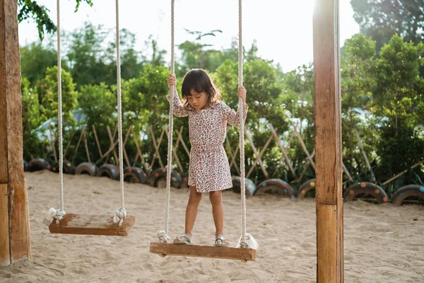 En liten flicka som står på trä swing ensam — Stockfoto