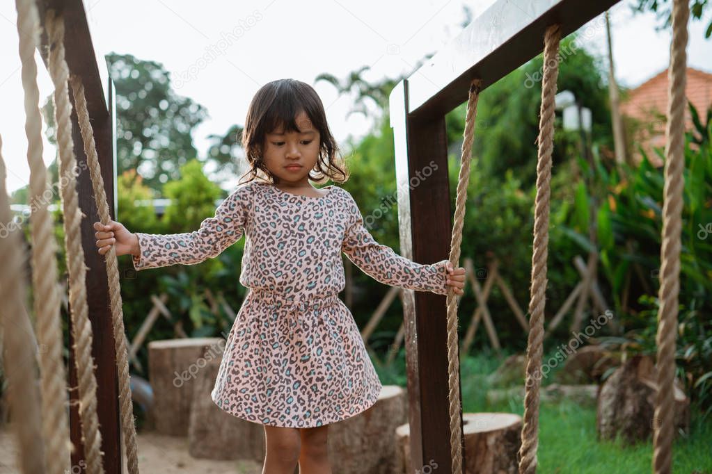 asian little girl very carefully hold a rope when standing on a balance beam